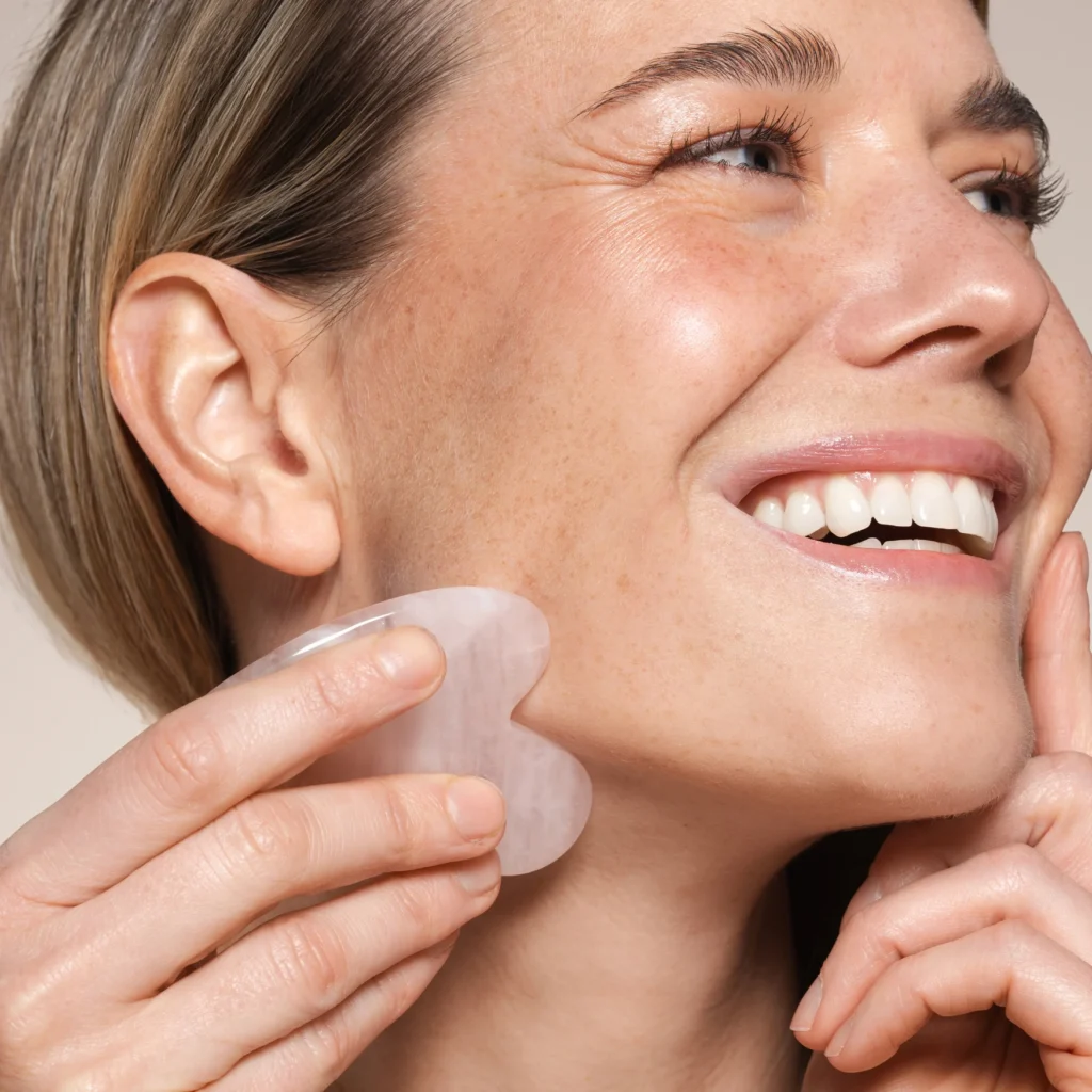 een vrouw met een stralende huid die een guasha gebruikt